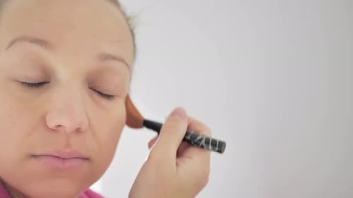 Woman Applying Makeup to Her Face with Brush