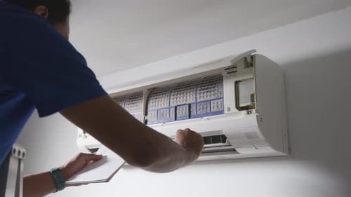 Professional technician male with clipboard checking operation of air conditioner