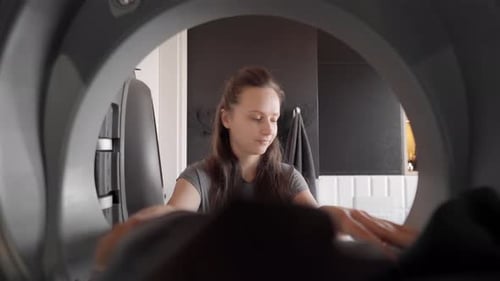 Inside dryer view. Housewife loading laundry into a dryer. Routine housework.
