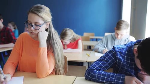 Schüler im Klassenzimmer machen gemeinsam einen Test, lernen und schreiben Notizen