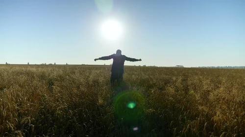 Farmer Businessman with Raised Hands Walks Through the Wheat Field at Sunrise