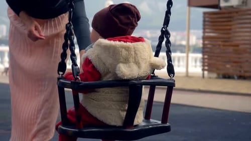 Familie, Mutterschaft - junge Mama schiebt ihr Baby auf die Schaukel