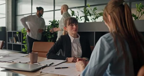 Two Women Conferring at Meeting in Modern Office