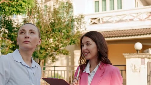 Two Businesswomen Talking Outside Cream Colored House