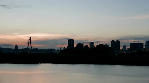 At dusk, the gorgeous sky and the silhouette of the city by the river.