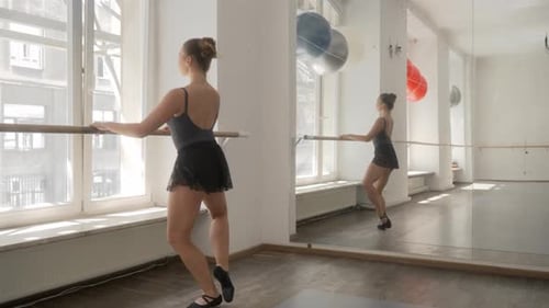 Elegant Ballet Dancer Practicing at Barre in Studio