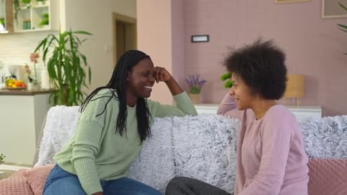 Women Chatting and Smiling on Couch at Home