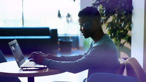 Young Adult Works on Laptop with Headphones