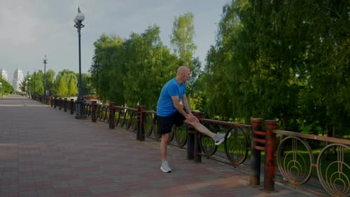 Determined Sporty Fitness Mature Man Stretching Legs Before Run at Sunrise