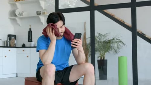 Man Resting and Using Phone after Home Workout