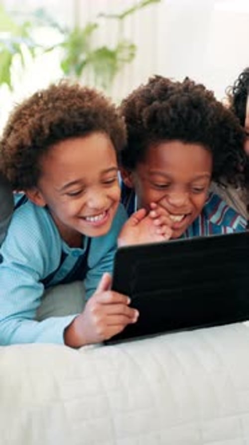 Boys Laughing Together Watching Tablet on Bed