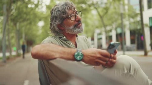 Mature Man Relaxing on Park Bench with Phone