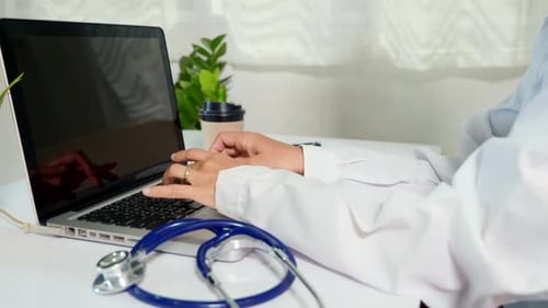 Doctor Typing on Laptop at White Desk