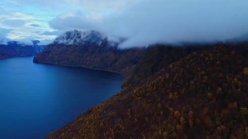 Aerial view panning out revealing mountains lake and clouds in Norway