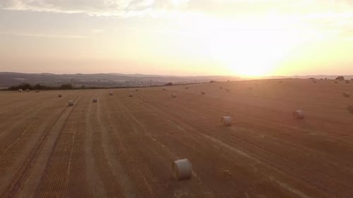 aerial view of harvested field with straw bales in sunset
