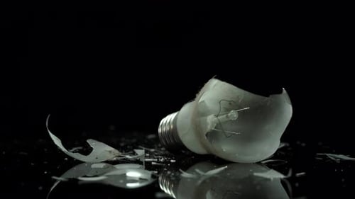 Glühlampe, zerbrochene Glühbirne an kleinen Glasstücken, Konzept zur Energielösung