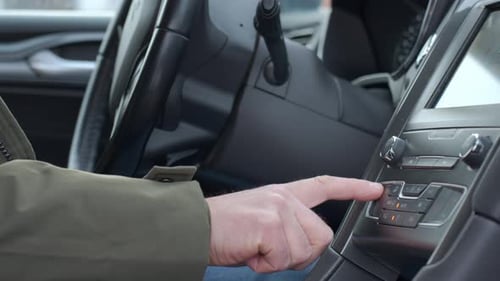 Finger pressing car climate control button on dashboard