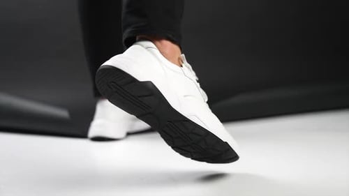 Fashionable White Sneakers on Legs Walking