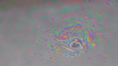 Crazy colorful pattern dancing around in a chaotic way. Macro shot of a soapy water film.