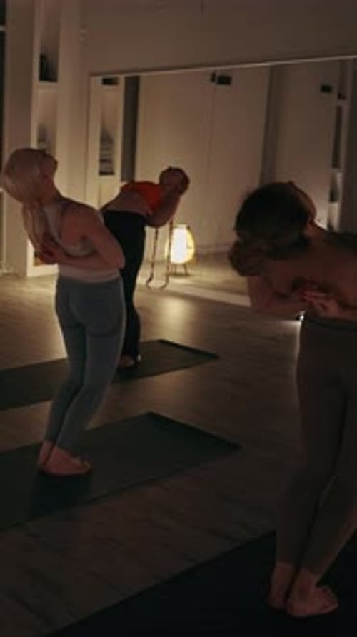 Pantalla vertical: mujeres realizando una postura inclinada hacia atrás en la clase de yoga