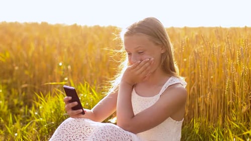 Teen Girl Using Phone in Golden Wheat Field