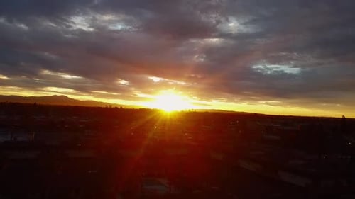 Sun rays through clouds over cityscape, drone shot.