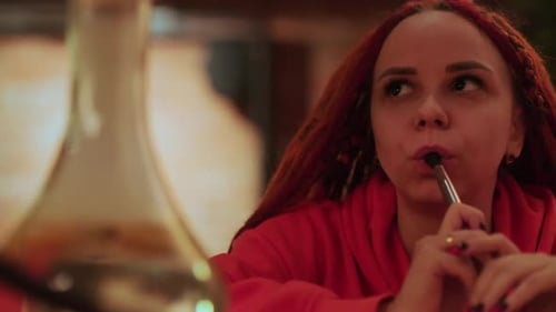 Young Woman with Dreadlocks Smoking Hookah Sitting in Hookah Bar