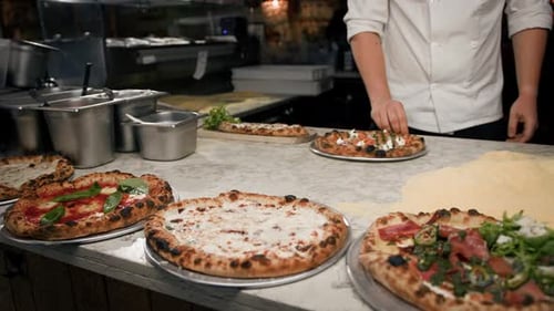 Ein professioneller Koch gibt den Kellnern die zubereiteten Pizzen: Margherita, 4 Käsesorten, Pizza mit Fisch