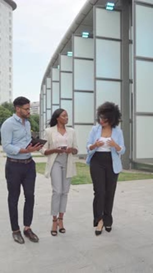 three multiethnic Business coworkers walking and discussing a project outdoors