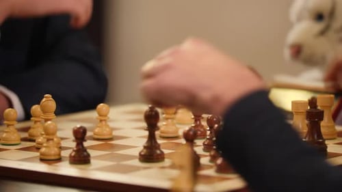 Nahaufnahme eines Schachbretts, während Geschäftsleute darauf Schnellschach spielen.