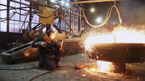 Metal Workers Welding with Sparks in Industrial Setting