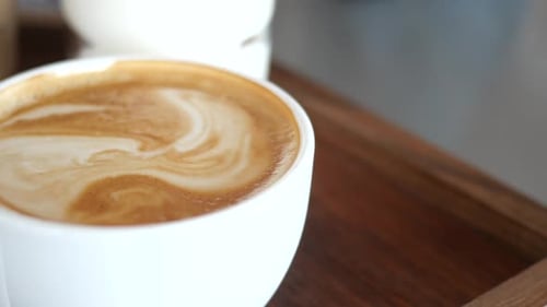 Genießen Sie einen köstlichen cremigen Kaffee mit wunderschöner Latte-Art, präsentiert auf einem rustikalen Holztablett