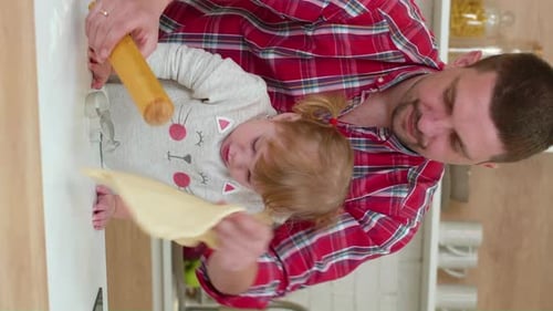 Padre e hija con pantalla vertical divirtiéndose cocinando juntos