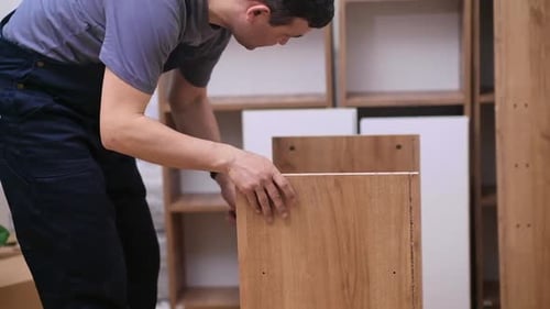 Man Assembling a Wooden Shelf Indoors
