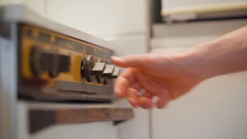 Hand Adjusting Dials on Kitchen Stove Appliance