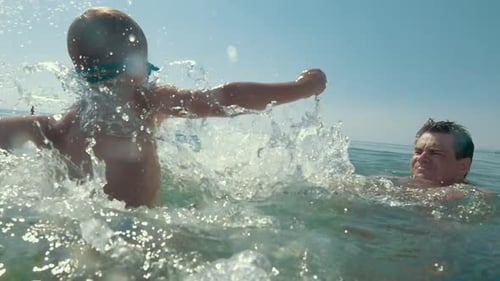Boy Spinning Around and Splashing in the Sea