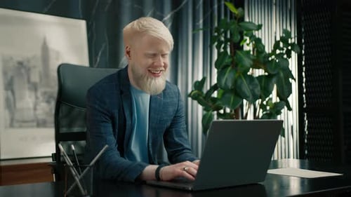 Smiling Albino Entrepreneur Reading Good News on Laptop Screen