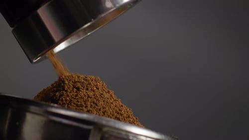 Ground Coffee Being Poured Into Metal Container