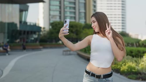Portrait of Woman with Long Hair Takes Selfie on Cellphone in Urban District