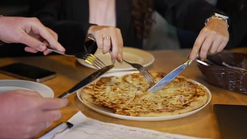 Eating pizza during lunch break. Colleagues cutting pizza in the company cafeteria.