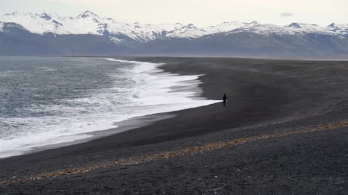 Man By Tide on Black Sand Beach