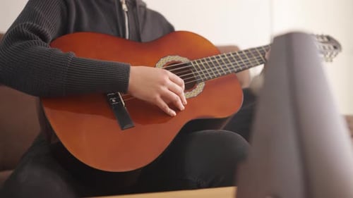 Young Adult Plays Acoustic Guitar in Relaxed Setting