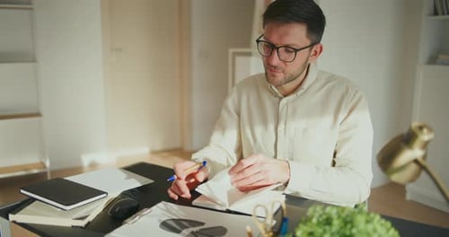 Man Writes in Notebook at Desk in Office