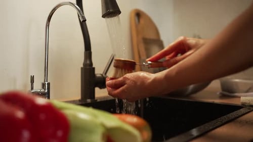 Hands washing red vegetable in kitchen sink