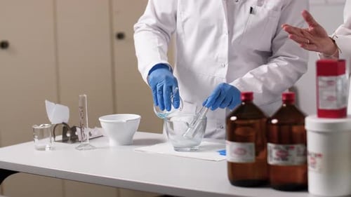 Un liquide est rempli dans un bol en verre. La PTA porte des gants et l'environnement est stérile
.