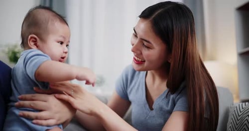 Eine asiatische Mutter spielt glücklich mit ihrem kleinen Sohn in einem warmen Zuhause.