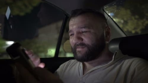 Man Using Phone in Taxi at Night