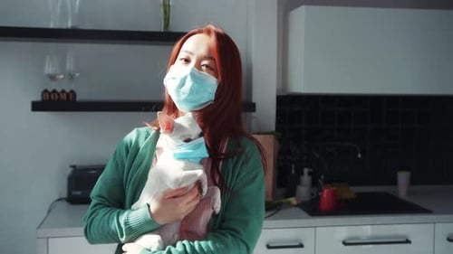 Pretty Young Asian Woman Holding White Cute Chihuahua Puppy in Hands Hugging and Wearing Medical