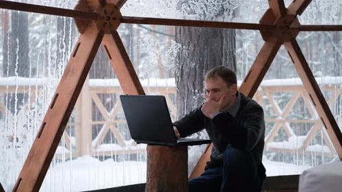 Man Works on Laptop in Snowy Dome
