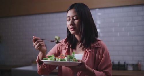 Woman Eats Healthy Salad in Modern Kitchen